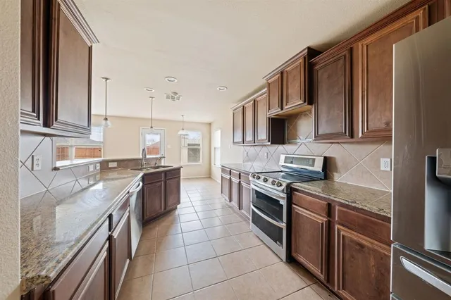 a kitchen with stainless steel appliances granite countertop a stove top oven a sink and a refrigerator