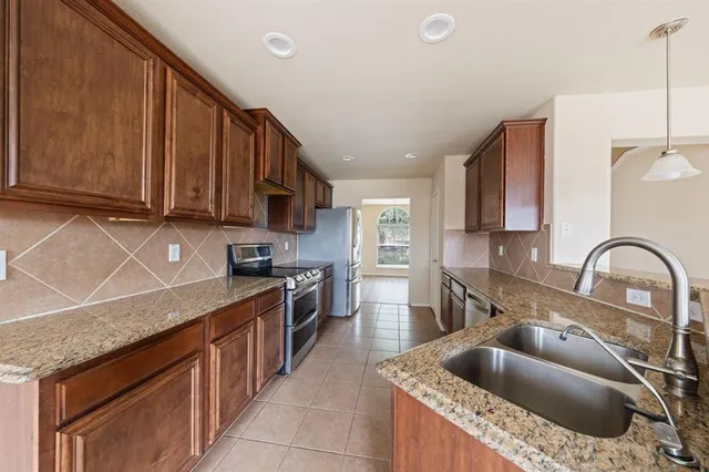 a kitchen with granite countertop a sink a counter space appliances and cabinets
