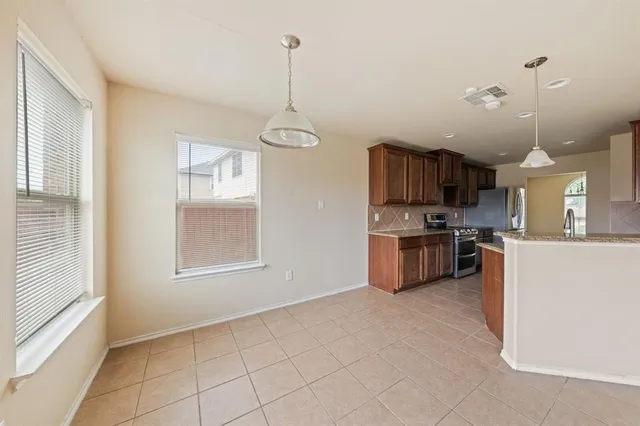a kitchen with granite countertop a stove a sink a refrigerator and a wooden floor