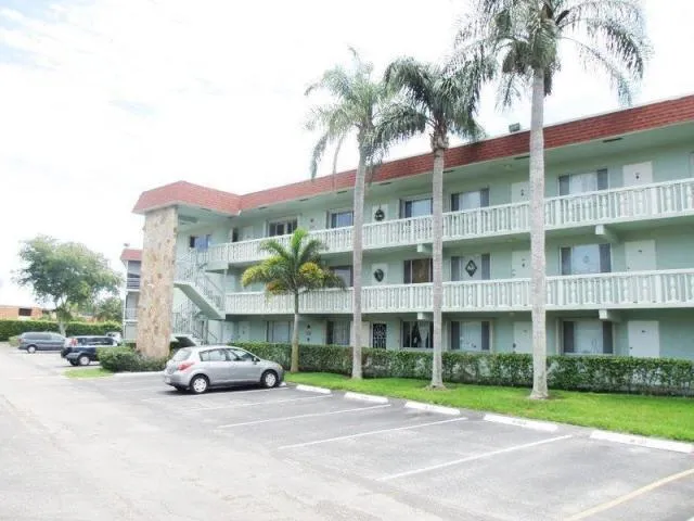 a view of a building with a yard and car parked