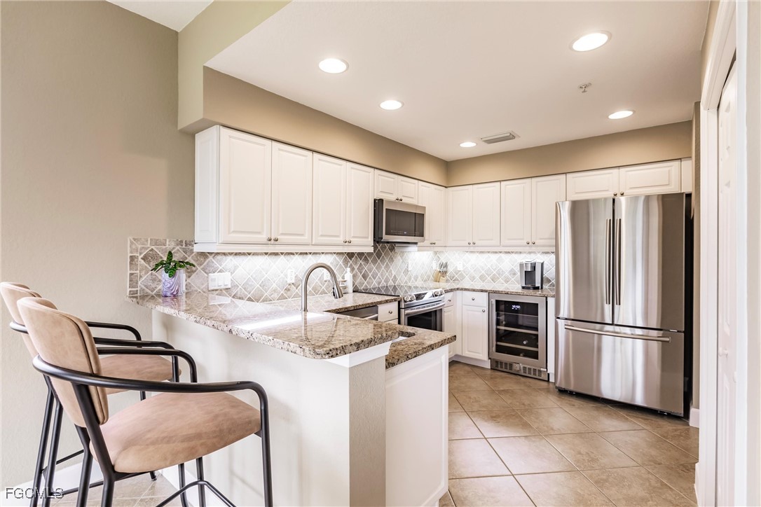 13120 Pebblebrook Point Circle, Unit 102 Fort Myers, FL 33905 - Photo 14 of 50 a kitchen with kitchen island a refrigerator stove and microwave