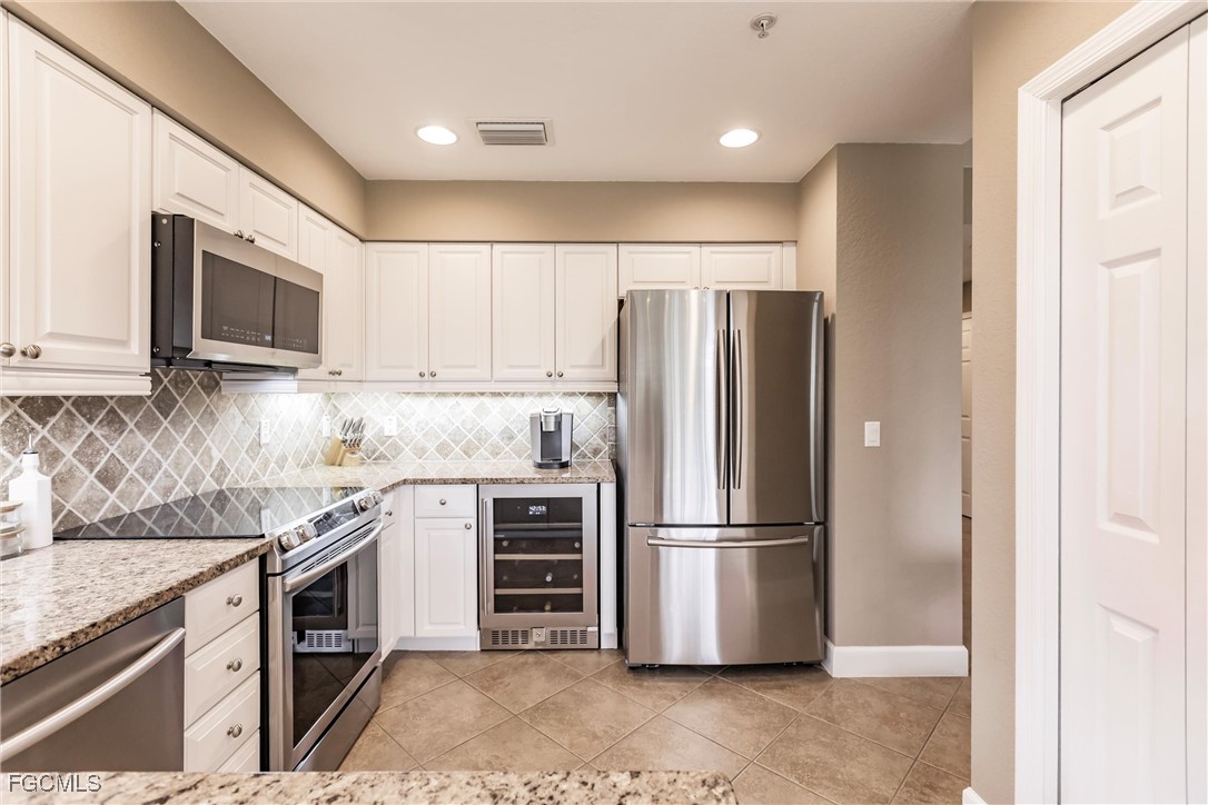 13120 Pebblebrook Point Circle, Unit 102 Fort Myers, FL 33905 - Photo 16 of 50 a kitchen with stainless steel appliances granite countertop a refrigerator a stove a sink and a microwave