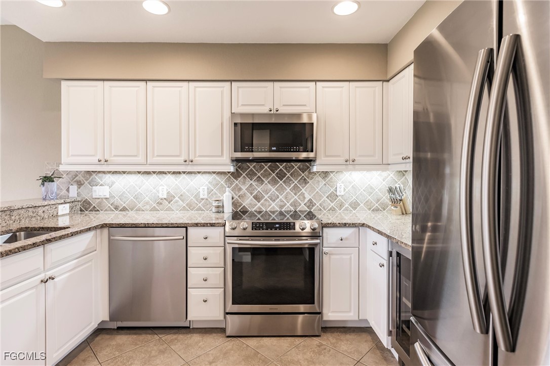13120 Pebblebrook Point Circle, Unit 102 Fort Myers, FL 33905 - Photo 17 of 50 a kitchen with white cabinets and stainless steel appliances