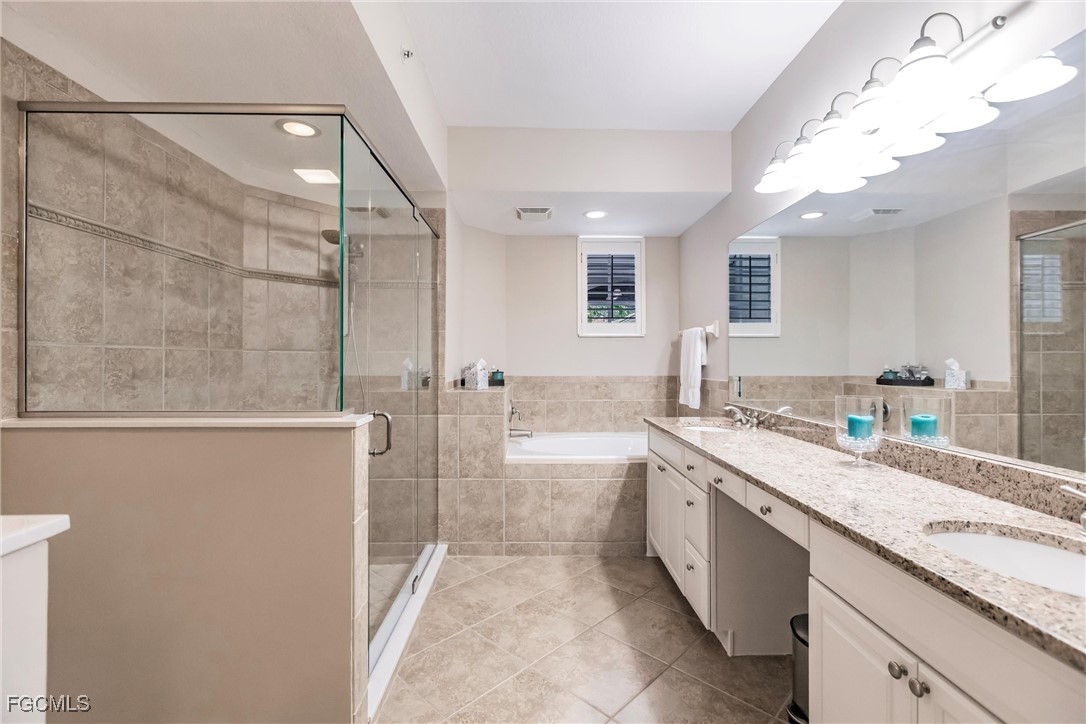 13120 Pebblebrook Point Circle, Unit 102 Fort Myers, FL 33905 - Photo 29 of 50 a spacious bathroom with a granite countertop sink a toilet a mirror and bathtub