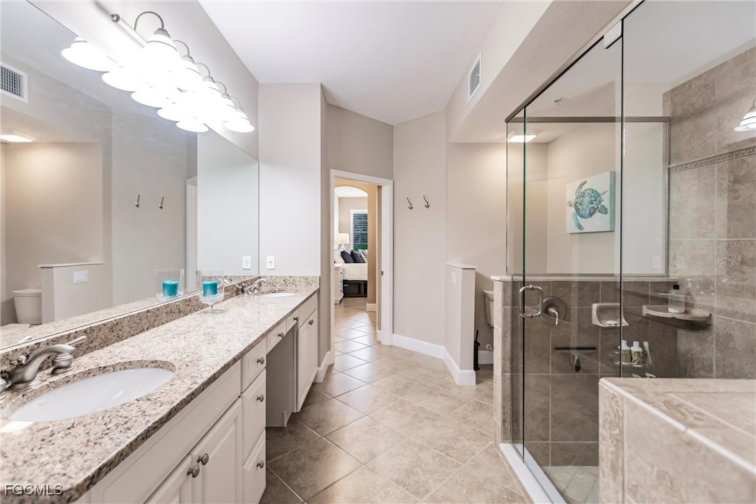 13120 Pebblebrook Point Circle, Unit 102 Fort Myers, FL 33905 - Photo 32 of 50 a spacious bathroom with a granite countertop double vanity sink a mirror and a shower