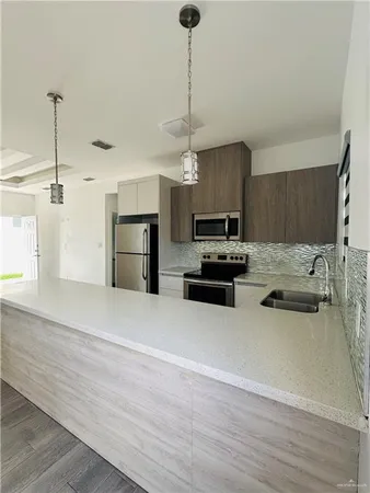 a kitchen with granite countertop a stove a sink and a refrigerator