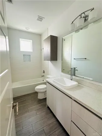 a bathroom with a granite countertop sink toilet mirror and bathtub