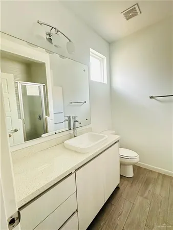 a bathroom with a granite countertop sink a toilet and mirror