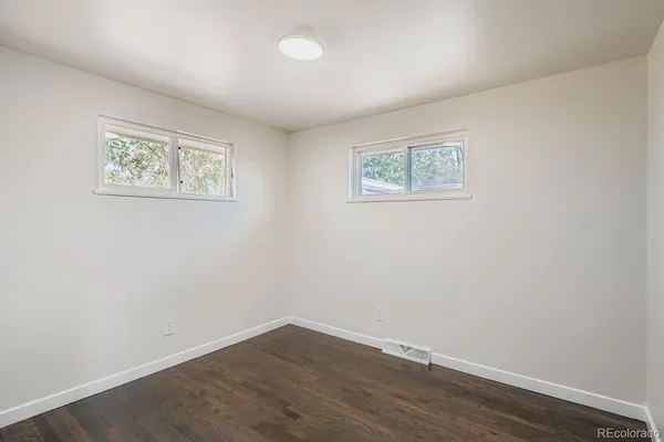an empty room with wooden floor and window