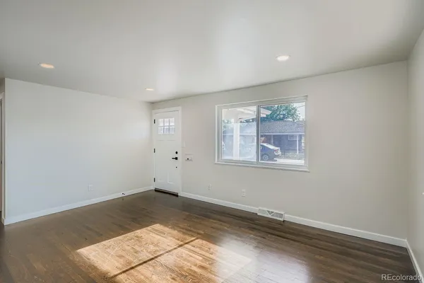 a view of a big room with wooden floor and windows