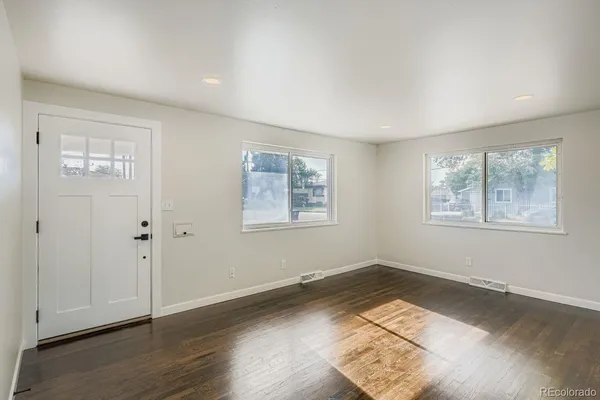 an empty room with wooden floor and windows