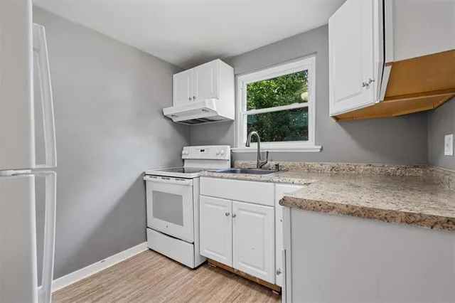 a kitchen with granite countertop a sink stainless steel appliances and cabinets