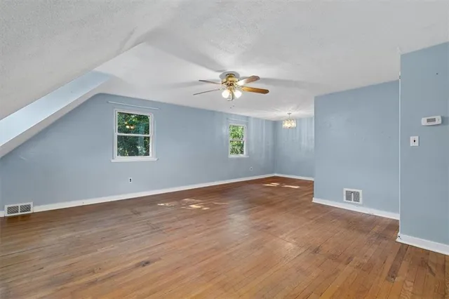 an empty room with wooden floor and a ceiling fan