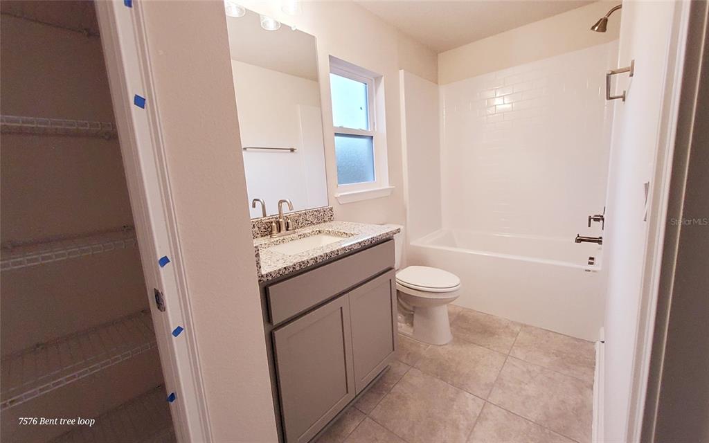7576 Bent Tree Loop St. Cloud, FL 34773 - Photo 11 of 18 a bathroom with a granite countertop sink a toilet and shower