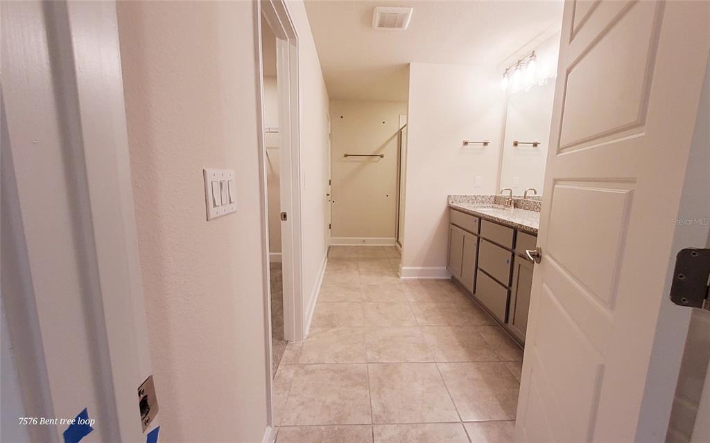 7576 Bent Tree Loop St. Cloud, FL 34773 - Photo 15 of 18 a bathroom with a granite countertop sink a mirror and a shower