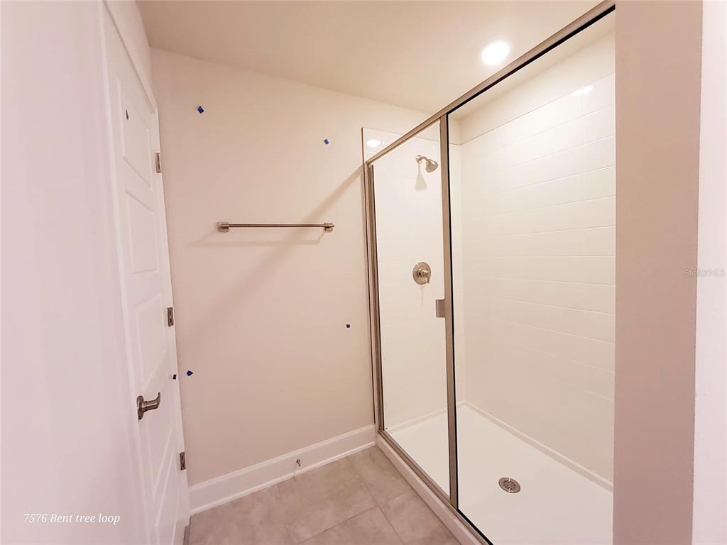 7576 Bent Tree Loop St. Cloud, FL 34773 - Photo 16 of 18 a bathroom with a glass shower door