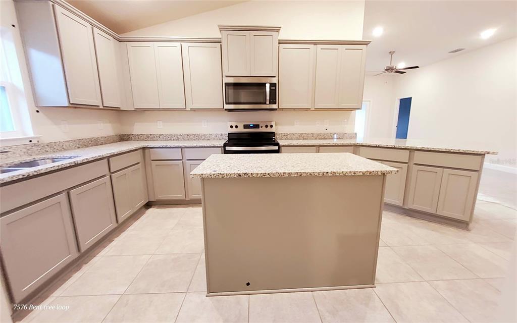 7576 Bent Tree Loop St. Cloud, FL 34773 - Photo 7 of 18 a kitchen with stainless steel appliances granite countertop a stove a sink and a microwave