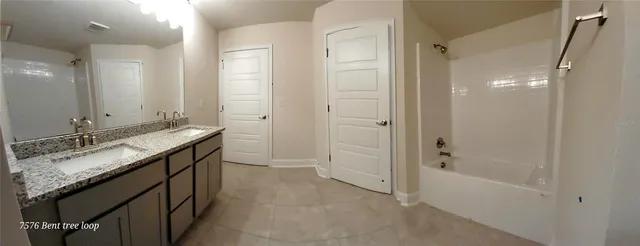 a bathroom with a granite countertop sink a mirror and a bathtub
