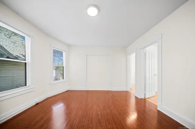 an empty room with wooden floor and windows