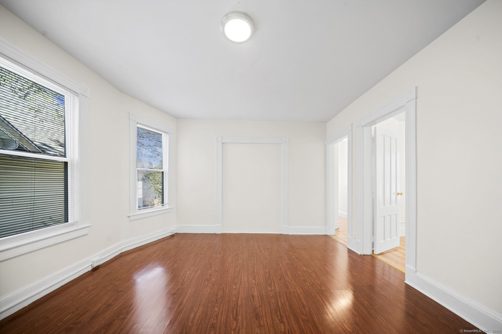217 Woodlawn Terrace Waterbury, CT 06710 - Photo 5 of 9 an empty room with wooden floor and windows