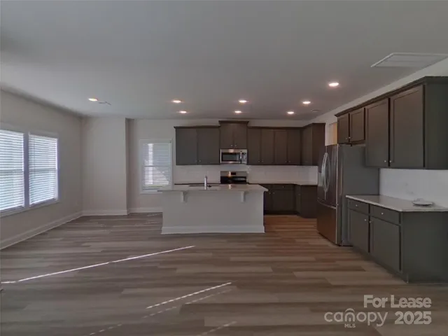 a view of kitchen with stainless steel appliances kitchen island wooden cabinets and granite counter top