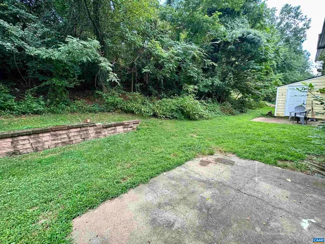 a view of a street with a small yard and large trees