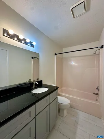 a bathroom with a granite countertop sink a toilet a mirror and shower