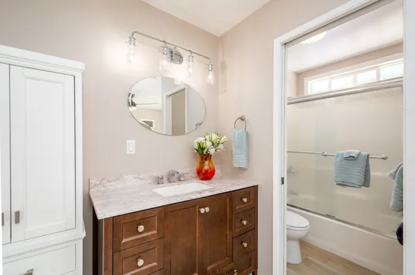 a bathroom with a granite countertop sink a toilet and shower