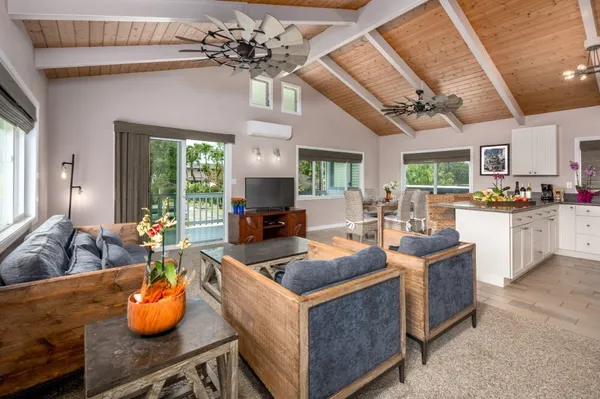 a kitchen with stainless steel appliances granite countertop a sink dishwasher a living room with couches and potted plants with wooden floor