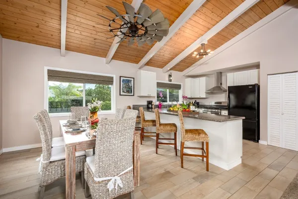 a dining room with stainless steel appliances granite countertop a table chairs and a refrigerator