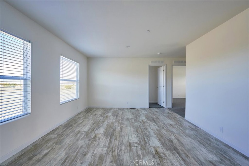 5430 Luna Road Phelan, CA 92371 - Photo 20 of 34 an empty room with wooden floor and windows