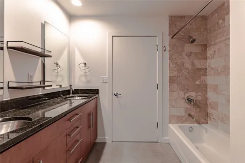a bathroom with a granite countertop sink mirror and a bathtub