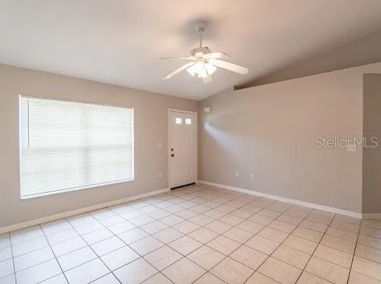 an empty room with chandelier fan and window