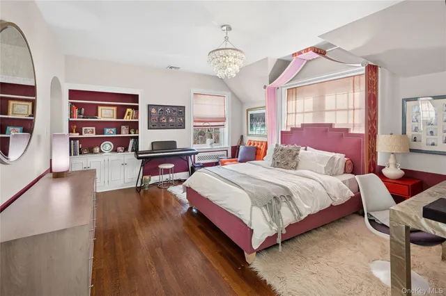 a spacious bedroom with a bed and wooden floor