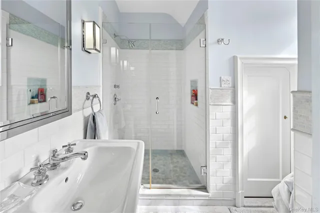 a bathroom with a tub shower sink and mirror
