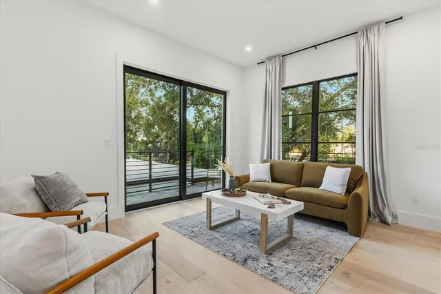 a view of an empty room with wooden floor fridge and a window