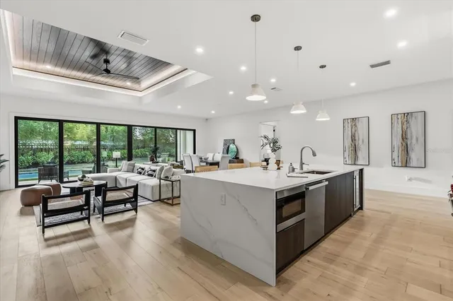 a kitchen with stainless steel appliances kitchen island granite countertop a stove top oven a sink dishwasher a dining table and chairs with wooden floor