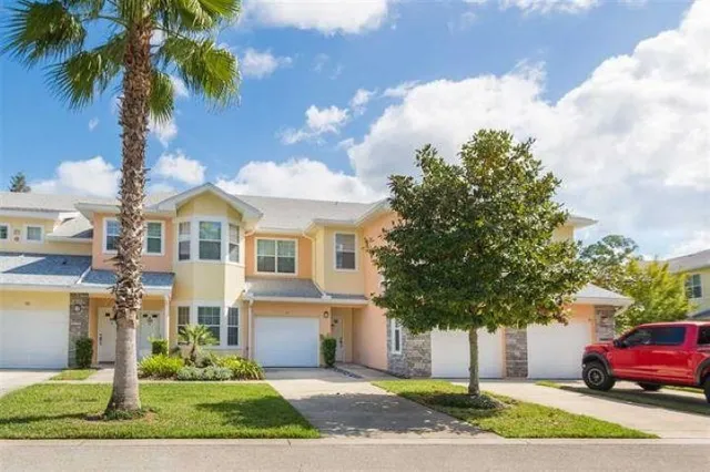 a front view of a house with a garden and tree