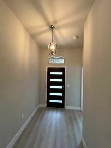 a view of a hallway with stairs and a chandelier