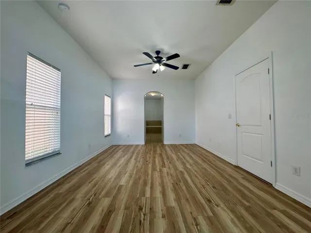 a view of empty room with wooden floor and fan