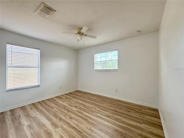 an empty room with a window and a fan