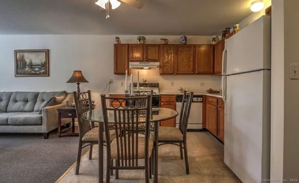 a kitchen with stainless steel appliances kitchen island granite countertop dining table chairs and a refrigerator