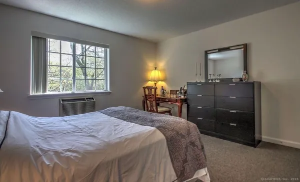 a bedroom with a bed and a dresser next to a window