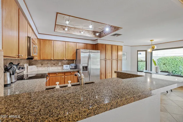 a kitchen with stainless steel appliances granite countertop a refrigerator a sink a stove a washer dryer and a refrigerator