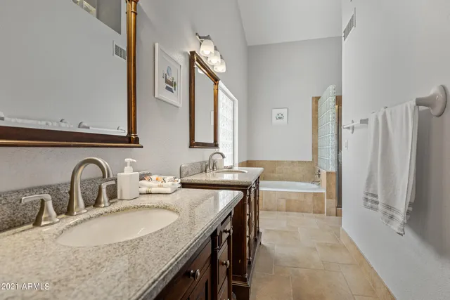 a bathroom with a granite countertop sink a mirror and a bathtub