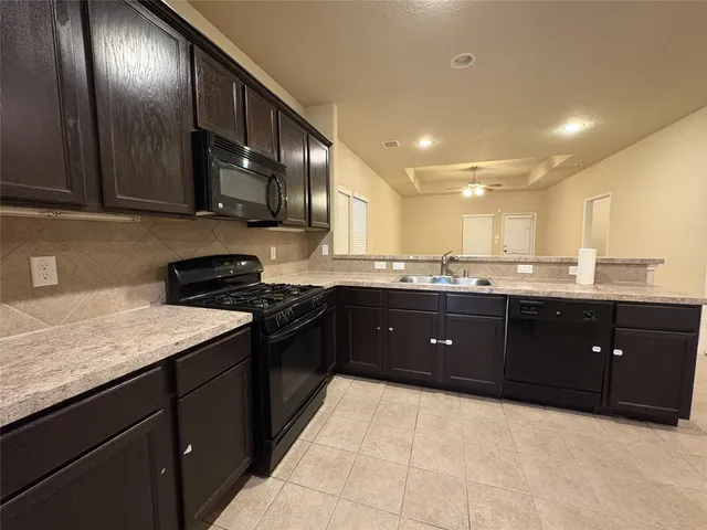 a view of a livingroom with a chandelier fan and kitchen view