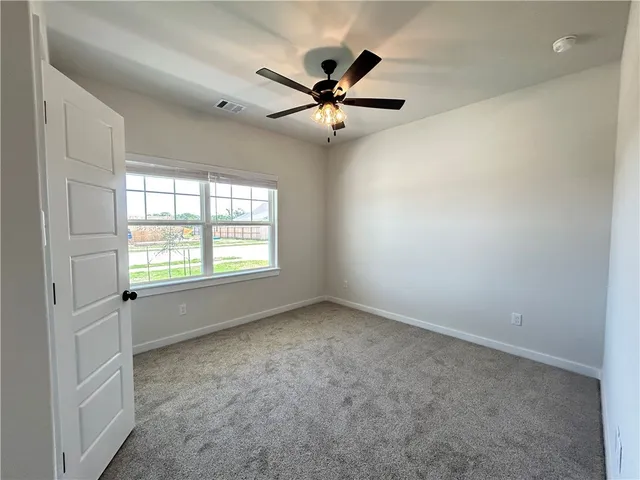 an empty room with windows and fan