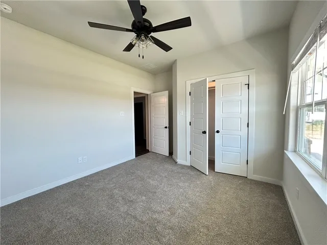 an empty room with windows and fan chandelier