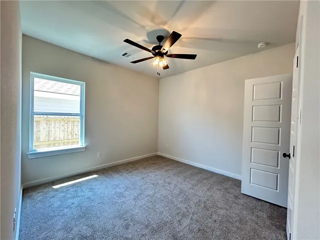 an empty room with windows and fan
