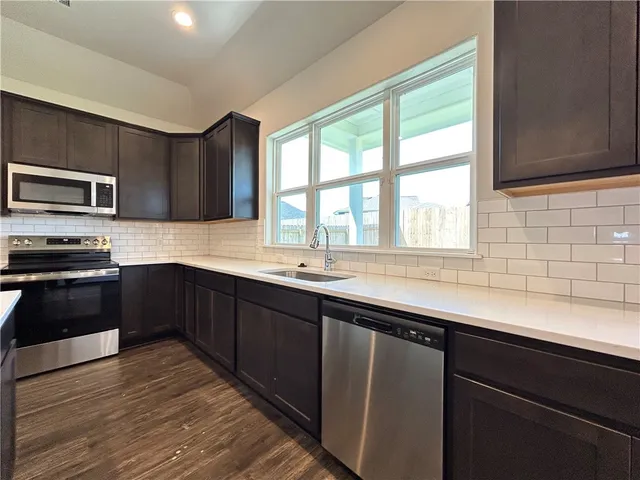 a kitchen with granite countertop a sink and steel appliances